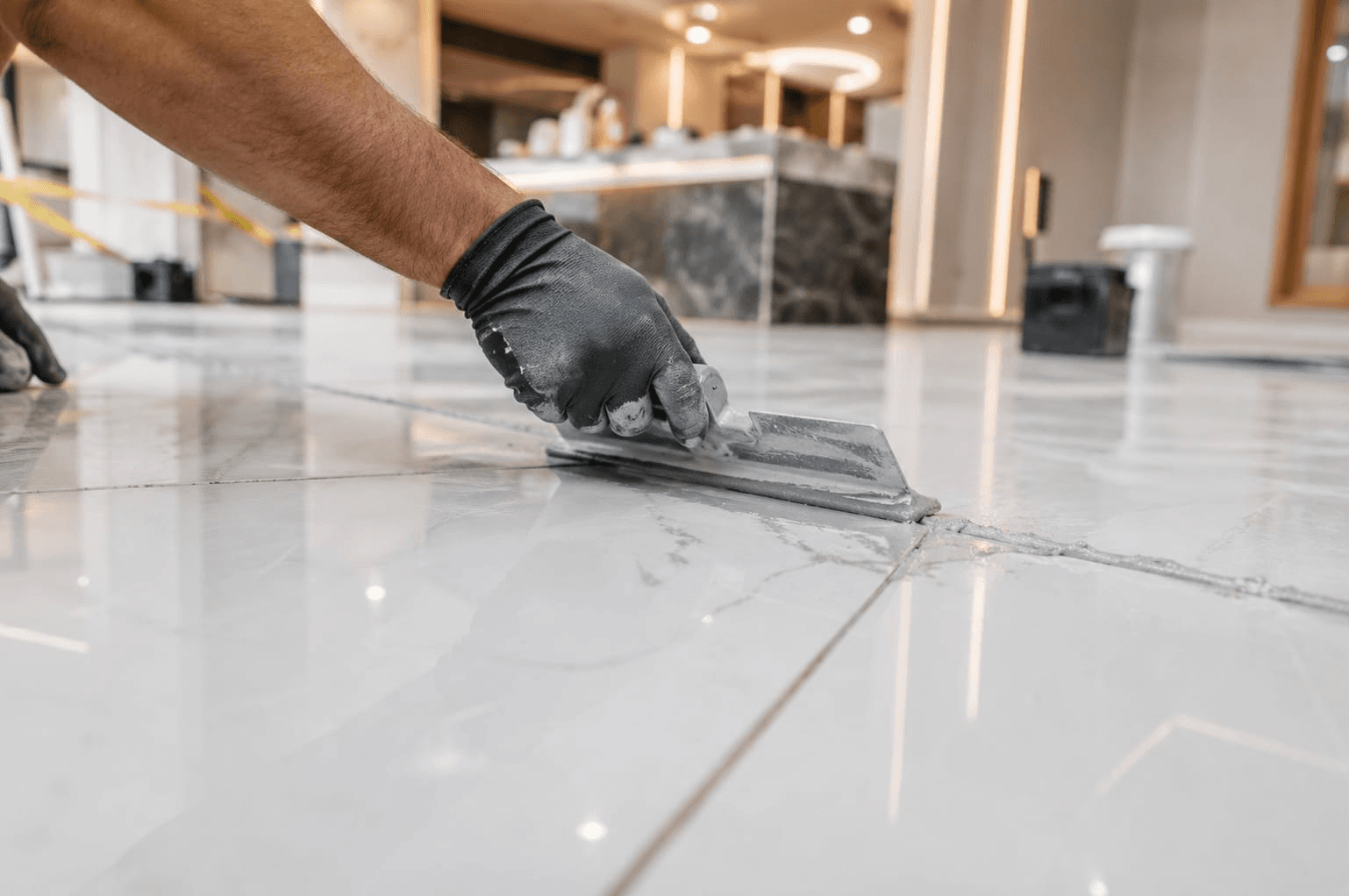 Worker using a squeegee to fill tile joints with epoxy grout